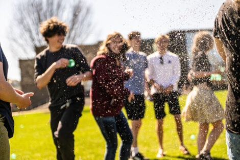 Students throw water balloons at each other.
