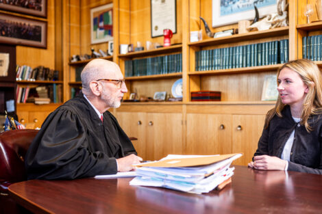 A judge sits across from the students with a pile of papers in between them.