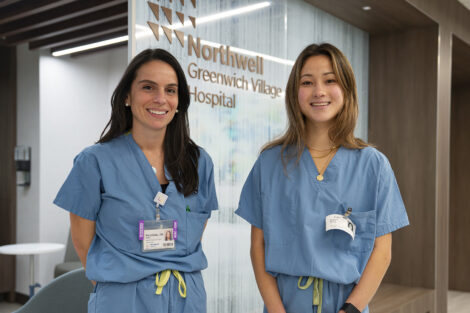 Two people standing wearing medical scrubs.