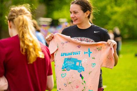 A student smiles, holding a springfest shirt.