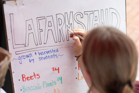 A student draws a sign that reads 