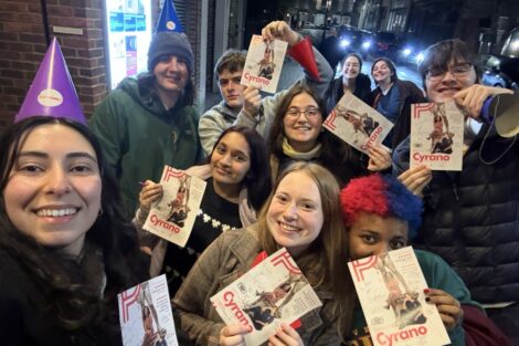 Students smile, holding playbooks that read 