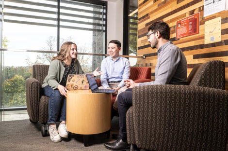 Students and their professor talk at chairs.