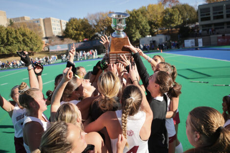 Field hockey players hold up the championship trophy