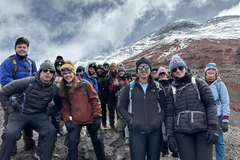 Students smile in front of a snow-covered mountain.