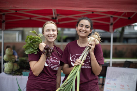 Two students holding produce