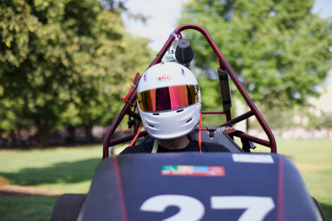 A student in a helmet rides a cart.